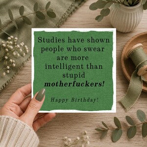 May include: A square greeting card with a textured green background and black text that reads: Studies have shown people who swear are more intelligent than stupid motherfuckers! Happy Birthday! The card has a white border.