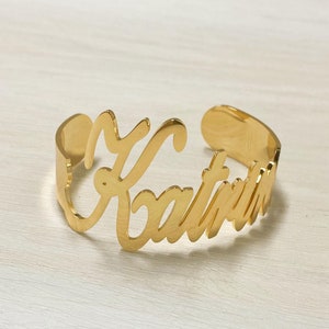 May include: Gold-toned metal bracelet with the name "Katrina" engraved in a cursive font.