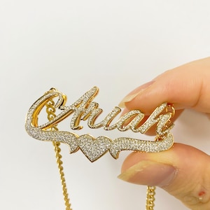 K&ouml;nnte beinhalten: Goldkette mit einem Herz-Anh&auml;nger und dem Namen "Anah" in funkelnder Schrift.