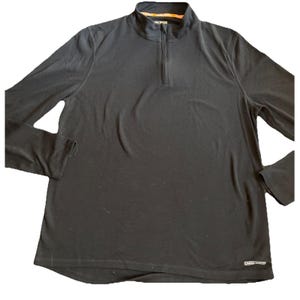 May include: A black long-sleeve pullover shirt featuring a quarter-zip neckline and a stand-up collar. The garment includes a small white Omni-Wick logo printed on the lower right side and a patterned orange and white inner neck lining.