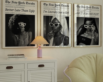 May include: Three framed black and white prints with the text "The New York Trends" and various headlines. A white cabinet with a lamp and a beanbag chair are in the foreground.