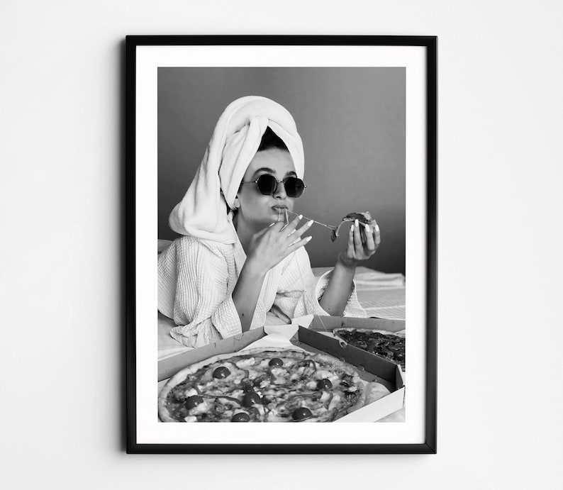Pu&ograve; includere: Stampa in bianco e nero incorniciata di una persona con occhiali da sole, un asciugamano e un accappatoio, che mangia la pizza. Due scatole di pizza sono aperte su un letto. Una pizza ha pomodori e l'altra ha condimenti scuri.
