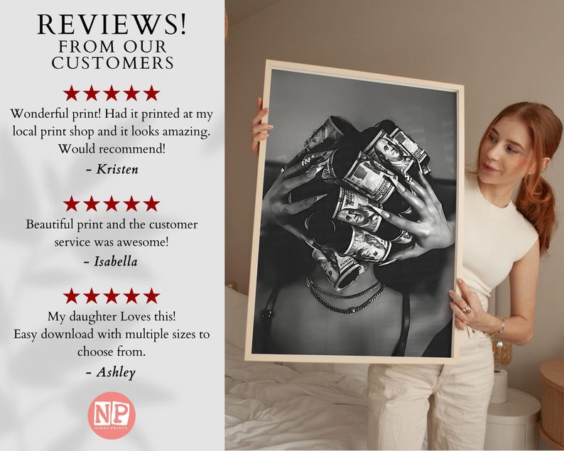 May include: Black and white print of a person with rolled-up US dollar bills covering their head. The print is held by a person wearing a white top and beige pants. The print is in a wooden frame.