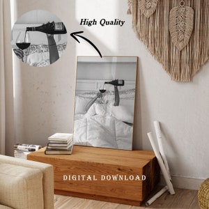 May include: Black and white print of a person in bed pouring wine into a glass. The image is framed in gold and has the words "High Quality" and "DIGITAL DOWNLOAD" on it. The print is displayed on a wooden table.