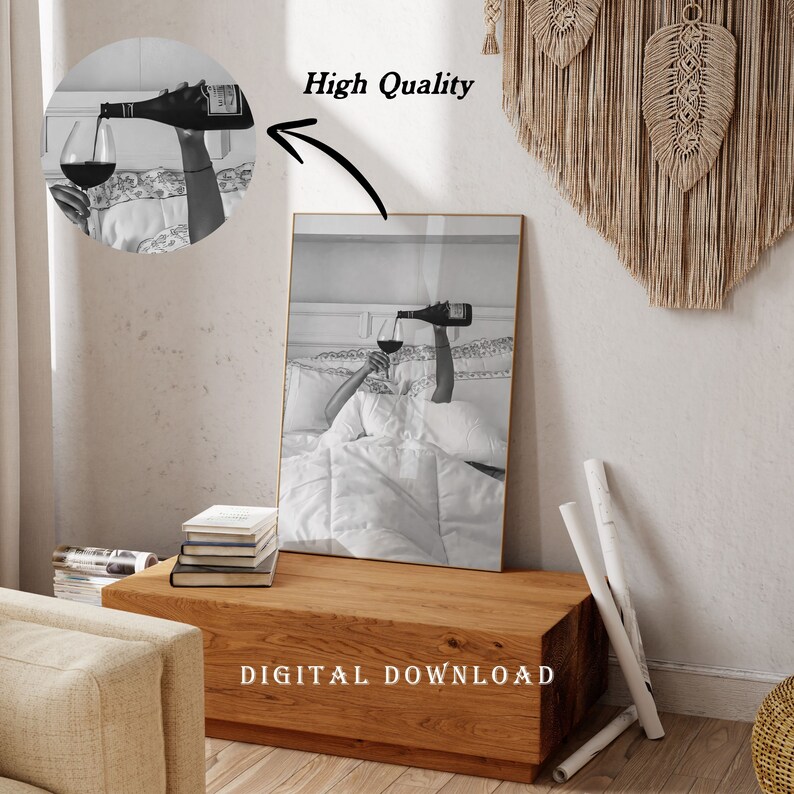 May include: Black and white print of a person in bed pouring wine into a glass. The image is framed in gold and has the words "High Quality" and "DIGITAL DOWNLOAD" on it. The print is displayed on a wooden table.