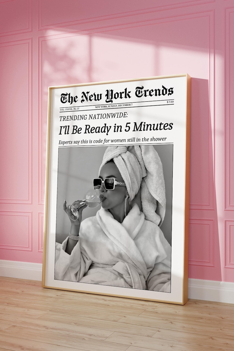 K&ouml;nnte beinhalten: Gerahmter Schwarz-Wei&szlig;-Druck einer Frau im Bademantel und Sonnenbrille, die ein Getr&auml;nk h&auml;lt. Der Druck ist ein Mock-Zeitungs-Cover mit dem Titel "The New York Trends" mit der Schlagzeile "I'll Be Ready in 5 Minutes."