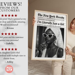 May include: A framed black and white print featuring a woman wearing sunglasses and applying lipstick. The print is designed to look like a newspaper, with the headline "I'm Literally Just a Girl."