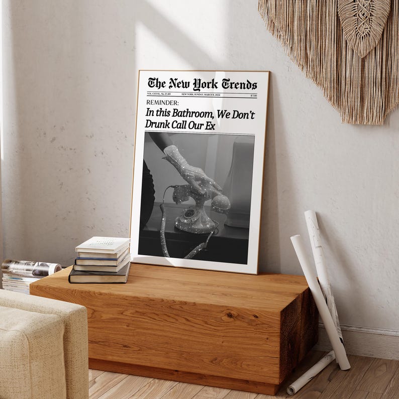 May include: A black and white photograph of a hand reaching for a rotary phone. The photo is framed and has the text "The New York Trends" and "REMINDER: In this Bathroom, We Don't Drunk Call Our Ex" printed on it.