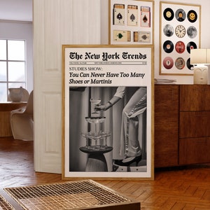 May include: A black and white photo of a woman wearing a white pantsuit and heels, reaching for a martini glass. The photo is framed and has the text "The New York Trends" and "STUDIES SHOW: You Can Never Have Too Many Shoes or Martinis" printed on it.