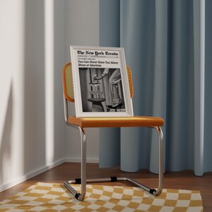 May include: A black and white photo of a woman in a dress and heels standing on a stack of martini glasses. The photo is framed in a white frame and is sitting on a yellow wicker chair. The text on the photo reads "The New York Trends" and "STUDIES SHOW You Can Never Have Too Many Shoes or Martinis".