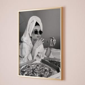 Pu&ograve; includere: Stampa in bianco e nero incorniciata di una persona con occhiali da sole e un asciugamano in testa, che mangia la pizza. Due scatole di pizza sono aperte di fronte a lei. La stampa &egrave; in una cornice dorata.