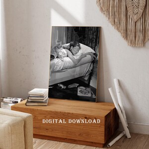 May include: Black and white photograph of a woman sleeping in bed with a cat. The woman is wearing a white shirt and has her eyes closed. The cat is curled up on the bed next to her. The photo is framed in a gold frame.