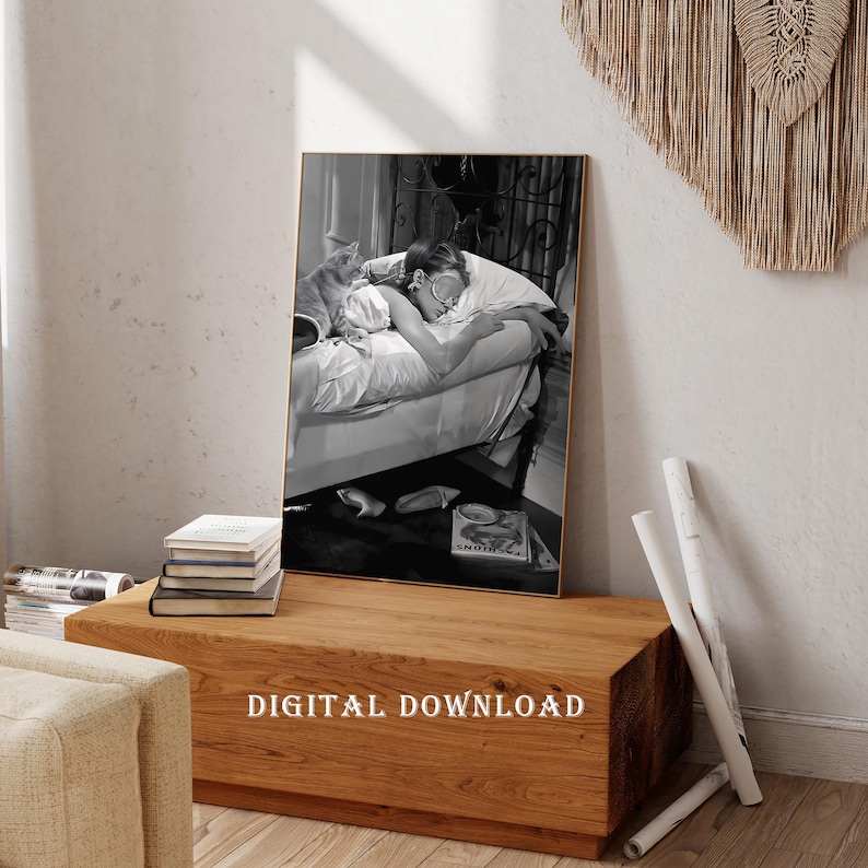 May include: Black and white photograph of a woman sleeping in bed with a cat. The woman is wearing a white shirt and has her eyes closed. The cat is curled up on the bed next to her. The photo is framed in a gold frame.
