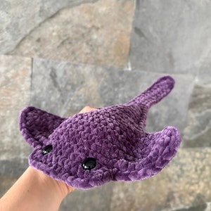 May include: A purple crocheted stingray plush toy with black eyes.