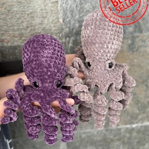 May include: Two crocheted octopus plushies, one purple and one light brown, with black eyes. The plushies are made with a soft, fuzzy yarn and have long, curled tentacles.