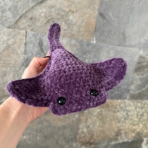 May include: A purple crocheted stingray plush toy with black eyes.