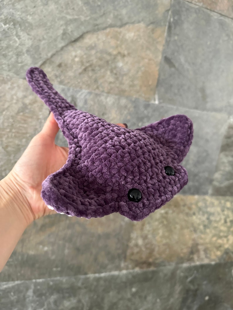 May include: A crocheted purple stingray plush toy with black eyes.