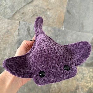 May include: A crocheted purple stingray plush toy with black eyes.