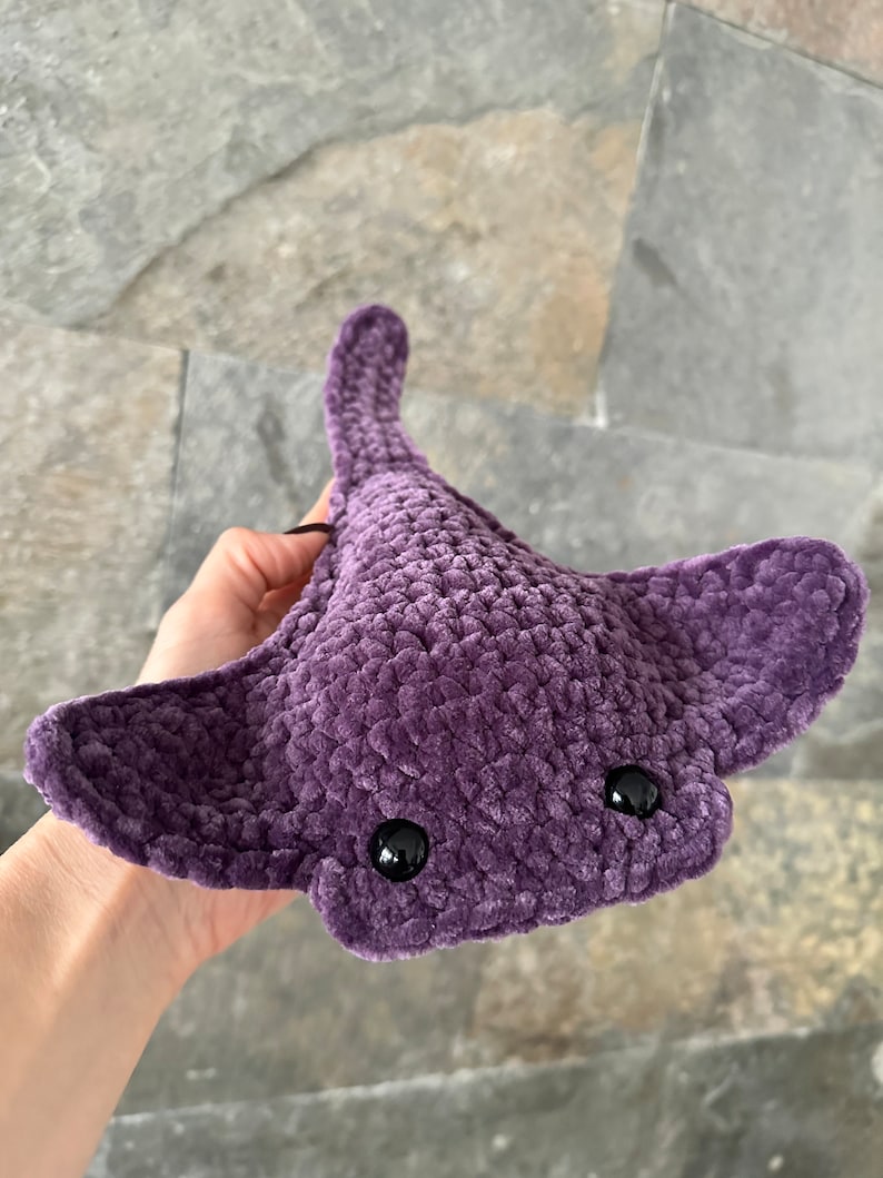 May include: A crocheted purple stingray plush toy with black eyes.