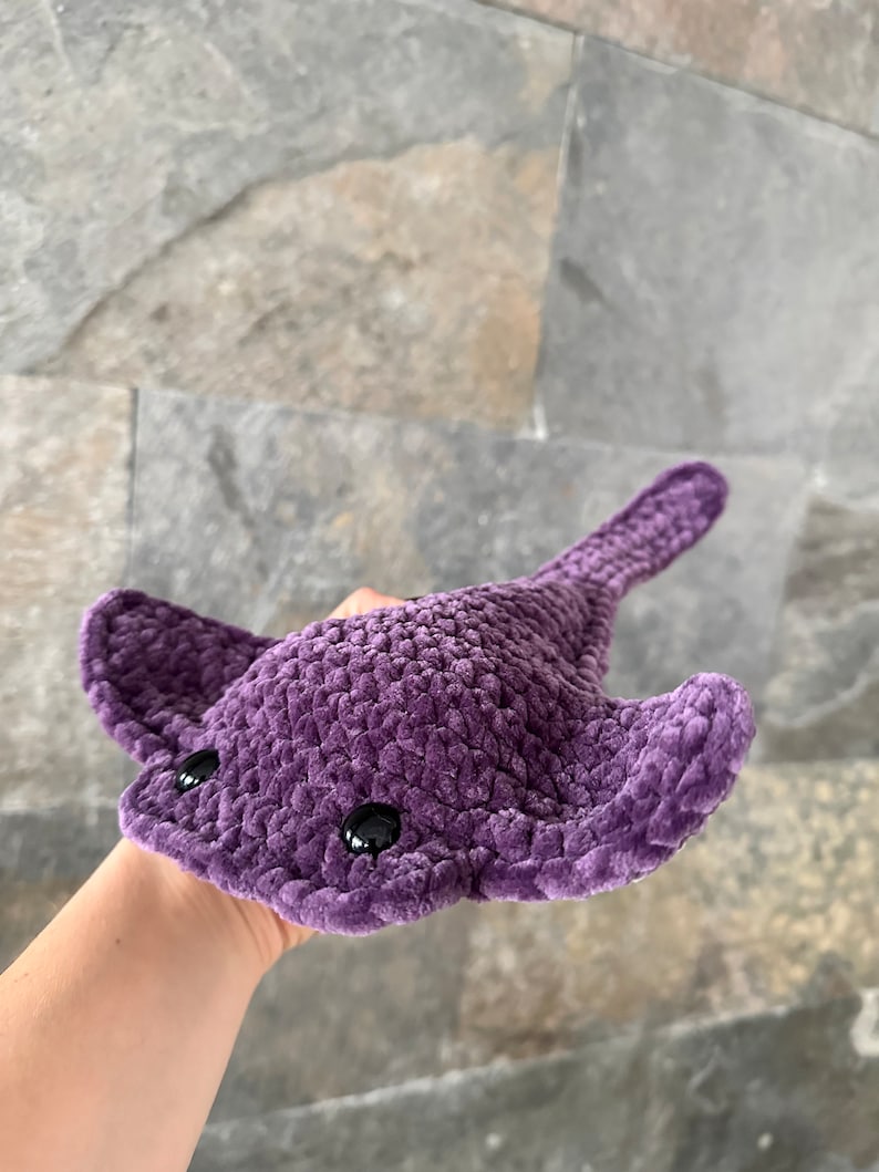 May include: A purple crocheted stingray plush toy with black eyes.