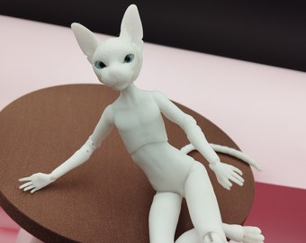 May include: White articulated doll with a cat-like face and blue eyes, sitting on a brown circular surface.