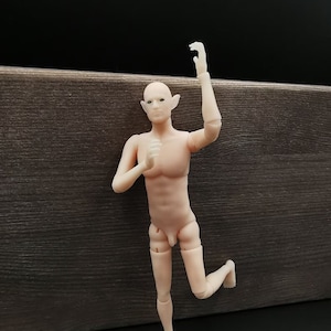 May include: A nude-colored articulated doll with pointed ears, standing with one leg raised and an arm raised above its head.