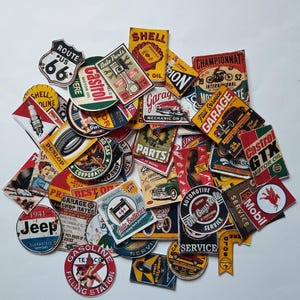 Könnte beinhalten: Eine Sammlung von Aufklebern im Vintage-Stil mit Automobil- und Tankstellenmotiven. Die Aufkleber zeigen Logos für Shell, Castrol, Texaco und Jeep sowie Beschilderungen der Route 66 und andere Retro-Designs. Die Farbpalette umfasst Rot, Gelb und Blau.