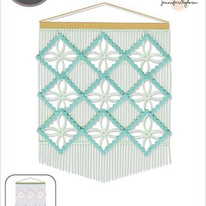 Op de afbeelding: Een macramé wandkleed met een geometrisch ontwerp. Het wandkleed heeft een lichtblauw en wit kleurenschema, met een houten deuvel aan de bovenkant. De afbeelding bevat ook de tekst "Sizzix" en "THINLITS".