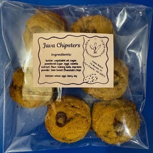 May include: A clear plastic bag contains six round, golden-brown cookies with chocolate chips. A label reads "Java Chipsters" and lists ingredients like butter, sugar, and chocolate chips. The cookies are home-baked.