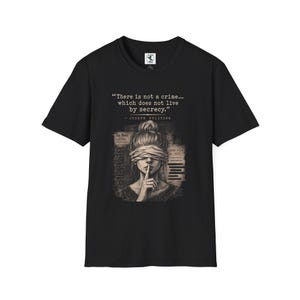 Op de afbeelding: Een zwart t-shirt met korte mouwen en een afbeelding van een persoon met een blinddoek en een vinger op de lippen. De tekst luidt: "There is not a crime... which does not live by secrecy." en "- JOSEPH PULITZER" boven de illustratie.