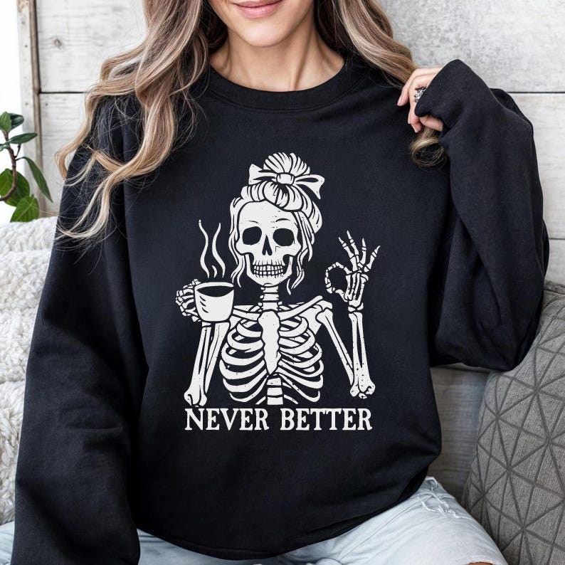 K&ouml;nnte beinhalten: Schwarzer Pullover mit einem wei&szlig;en Grafikdruck eines Skeletts, das eine Kaffeetasse h&auml;lt und "Never Better" sagt.