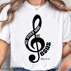 May include: White t-shirt featuring a black treble clef design with the words "NO OTHER NAME BUT Jesus" and the Bible verse "Acts 4:12". The design is centered on the front of the shirt.