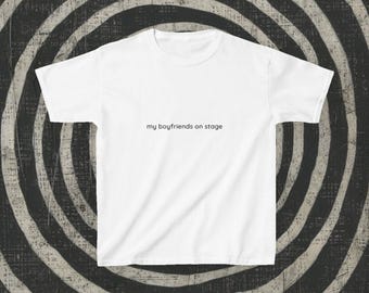 May include: White short-sleeve t-shirt with the text "my boyfriends on stage" in a black, simple font. The shirt is centered in the image, set against a black and white spiral background.