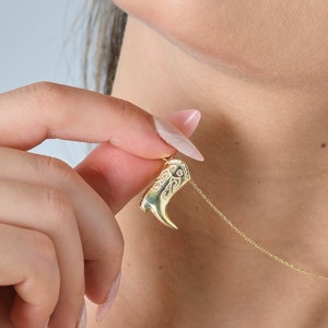 Pode incluir: Um colar de ouro com um pingente em forma de bota. A bota é detalhada com um design floral.