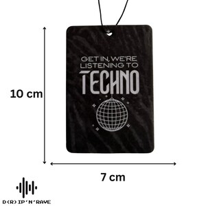 May include: Black air freshener with the text "GET IN, WE'RE LISTENING TO TECHNO" and a disco ball graphic. The rectangular freshener measures 3.9 inches wide by 2.8 inches tall. A black string is attached for hanging.