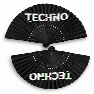 May include: Two black hand fans with the word "TECHNO" in white with green and pink shadow effects. The fans are open, showing their pleated design and a decorative semi-circle pattern.