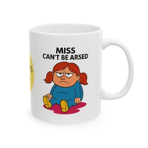 May include: White ceramic mug with a cartoon illustration of a grumpy girl with red pigtails and the text "MISS CAN'T BE ARSED". The girl is wearing a blue outfit and yellow shoes. A yellow sticker is on the side.