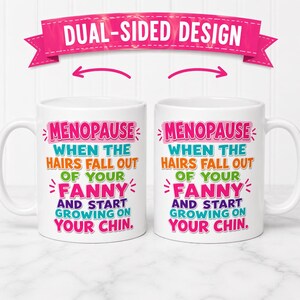 May include: Two white ceramic mugs with the text "MENOPAUSE WHEN THE HAIRS FALL OUT OF YOUR FANNY AND START GROWING ON YOUR CHIN." A pink banner above reads "DUAL-SIDED DESIGN."