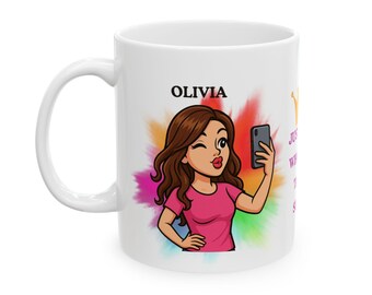 May include: White ceramic mug featuring a cartoon illustration of a woman taking a selfie. The mug has the name "Olivia" above the illustration and colorful paint splash background. Text on the mug reads "Just Wink With Me".