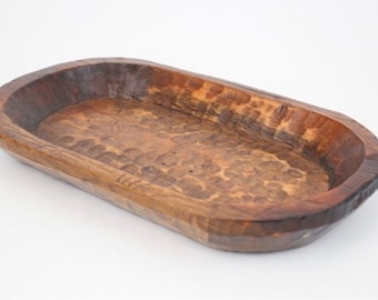 May include: A rustic wooden dough bowl with a natural brown finish. The bowl is oval shaped and has a slightly raised rim.