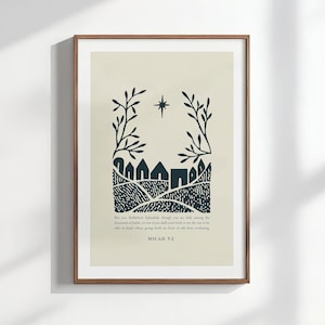 Peut inclure: Une affiche encadrée avec une illustration minimaliste bleu marine sur fond crème. L'œuvre représente un village avec une étoile et des feuilles. Le texte "MICAH 5-2" est visible en bas.