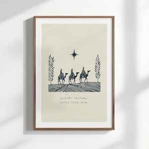 May include: Framed art print featuring a minimalist illustration of three figures on camels, a star, and the text "wise men still seek him." The artwork is in shades of blue and beige, with a simple, elegant design. The print is in a brown wooden frame.