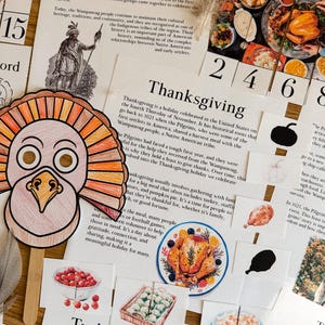 May include: A colorful paper turkey mask with orange, yellow, and red feathers. The mask is attached to a wooden stick. The text "Thanksgiving" is visible in the background.