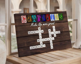 May include: A wooden sign with the word "GRANDKIDS" in colorful block letters. Below, the phrase "Make life more grand" is written in cursive. The sign features a crossword puzzle design with names like Martin, Michael, and Jeremy.