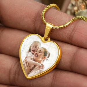 a person holding a heart shaped pendant with a picture on it