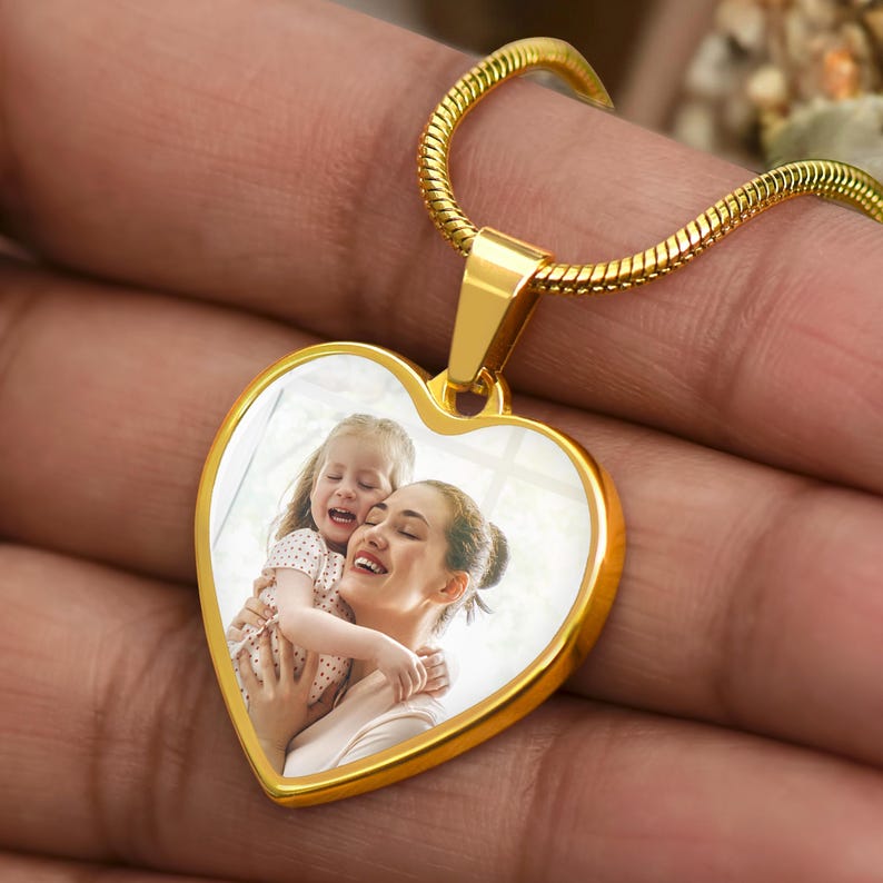 a person holding a heart shaped pendant with a picture on it