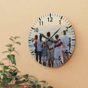 May include: A round clock with a photo of a family of five standing on a beach at sunset. The clock face has black numbers and hands.