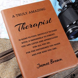 May include: A brown leather journal with the text "A Truly Amazing Therapist" and a quote about therapists. The journal is personalized with the name "James Brown".
