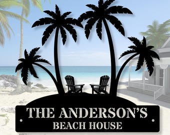 Puede incluir: Letrero de casa de playa de metal negro con palmeras, dos sillas y el texto "THE ANDERSON'S BEACH HOUSE". El fondo muestra una playa, el mar y el cielo.