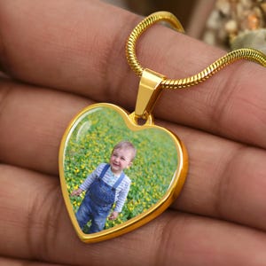 a person holding a heart shaped pendant with a picture on it